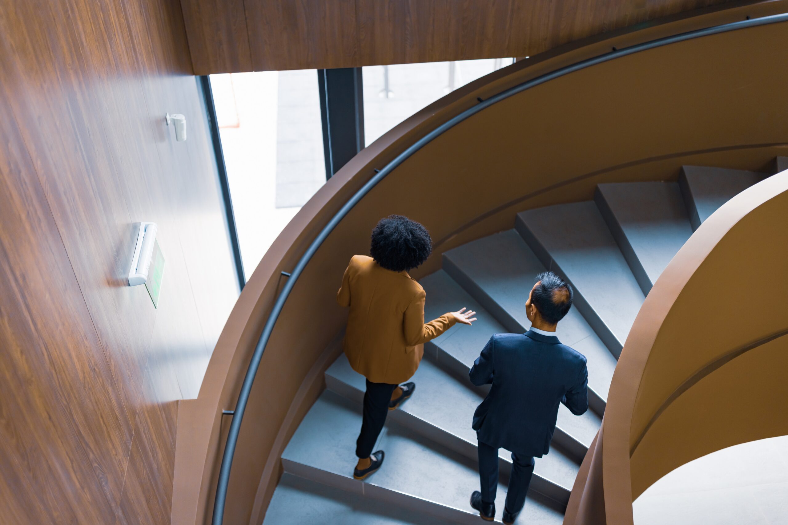 Two senior professionals in conversation on a curved staircase