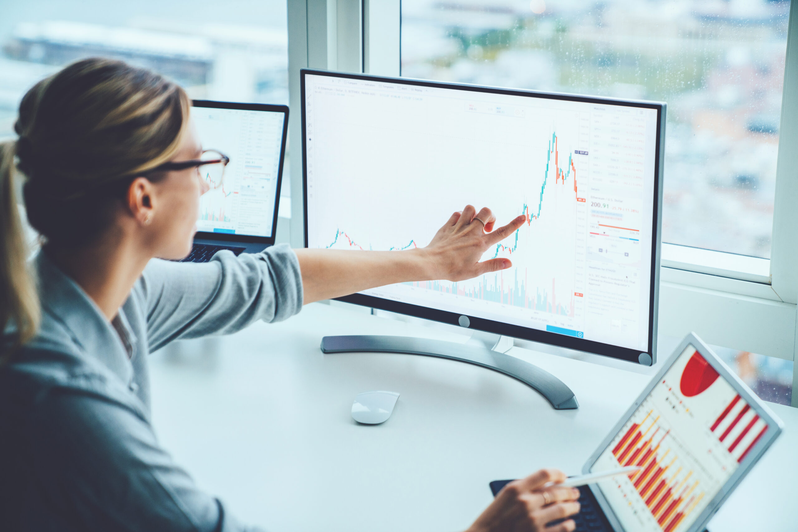 Financial analyst reviewing market data on multiple screens